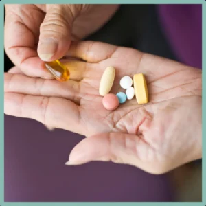 A hand holds several different types of medication.