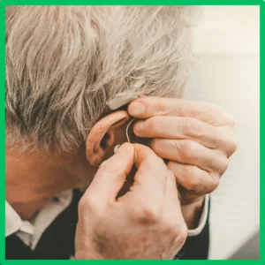 A man puts his hearing aid in. 