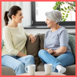 A younger woman talks to an older woman on a couch. 