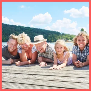 Grandparents and grandkids pose on a dock on a lake. 