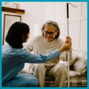 A caregiver helps an older patient stand. 