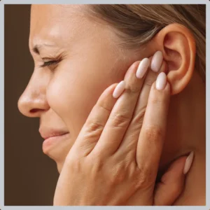 A woman holds her ear and grimaces.