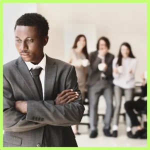 A man looks sad while people talk behind him. 
