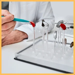 An audiologist points to a display of small hearing aids. 
