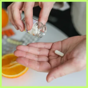 A person puts a supplement into their hand. 