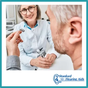 A man looks at a hearing aid with his audiologist.