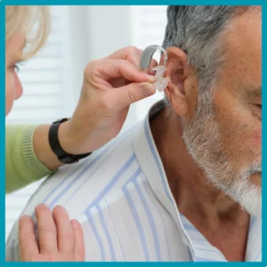 A woman places a hearing aid in her husband's ear. 
