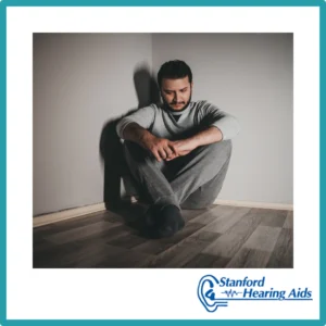 A depressed man sits in a corner. 