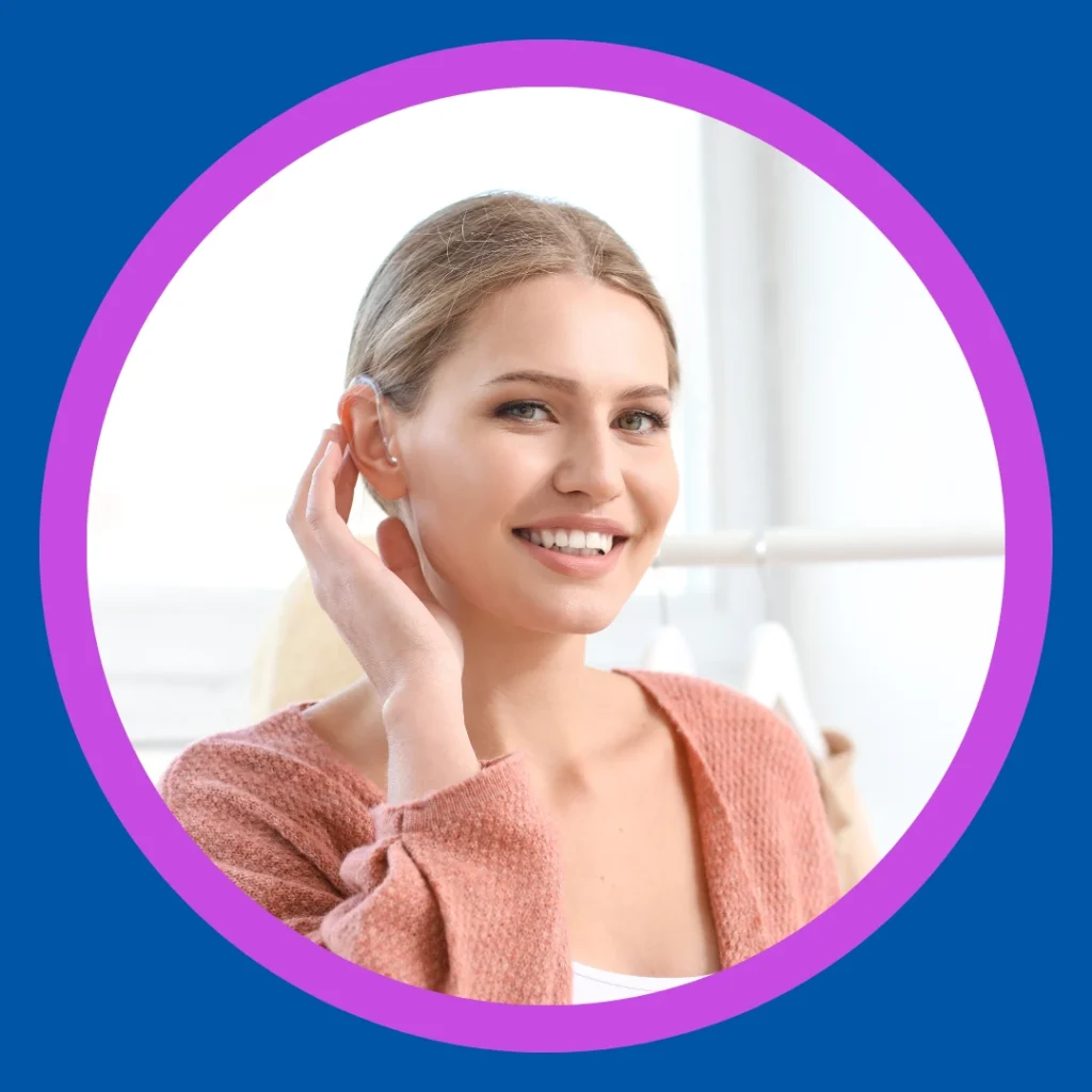 A smiling woman touches her hearing aid.