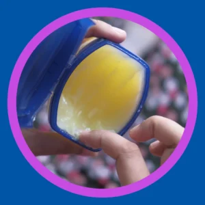 A finger reaches into a jar of petroleum jelly. 