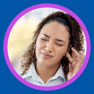 A woman holds her ear and grimaces. 