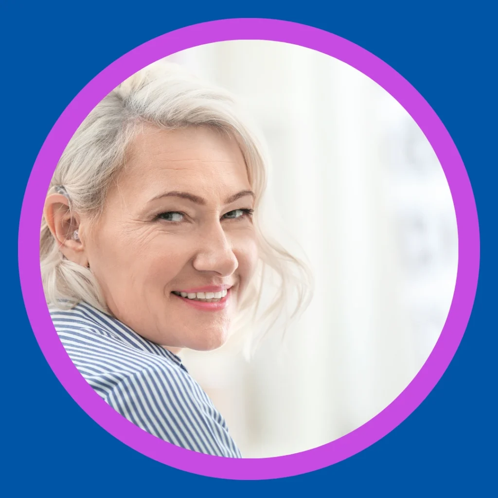 A woman wearing a hearing aid smiles happily.