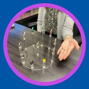 An audiologist points to a tray of hearing aids. 