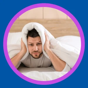 A man holds his ears while wide awake in bed. 
