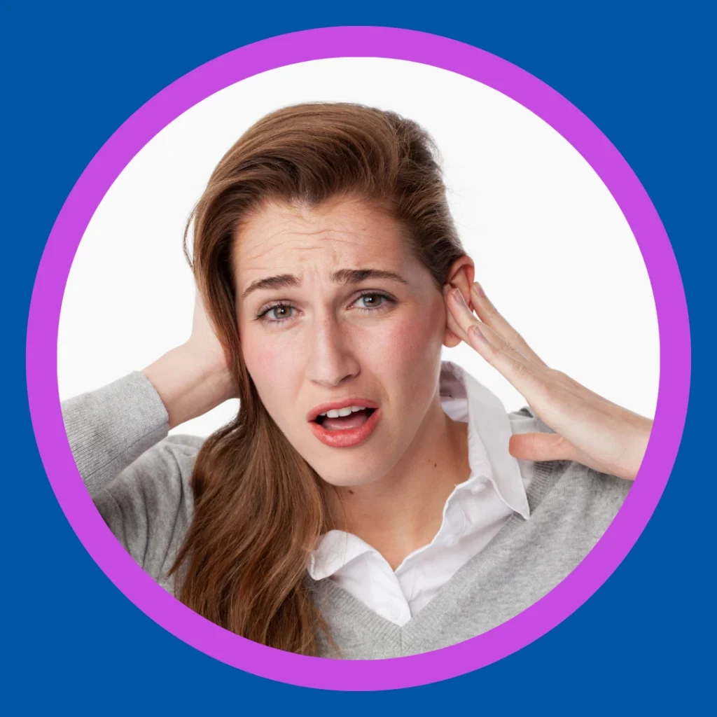 A woman grimaces and holds her ears.