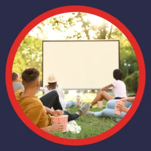 People watch an outdoor movie screen. 