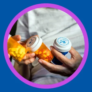 A hand holds 3 bottles of prescription medications. 