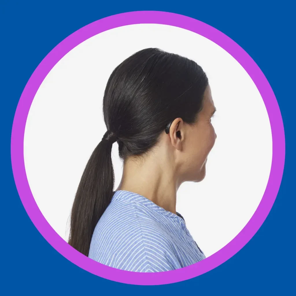 A woman faces away to show her small black hearing aid.